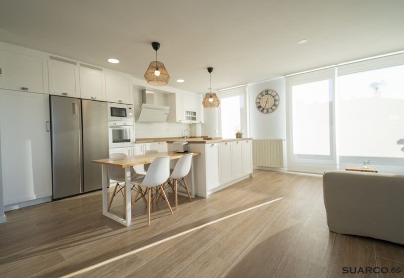 Cocina blanca con isla y encimera de madera. Cocinas Suarco