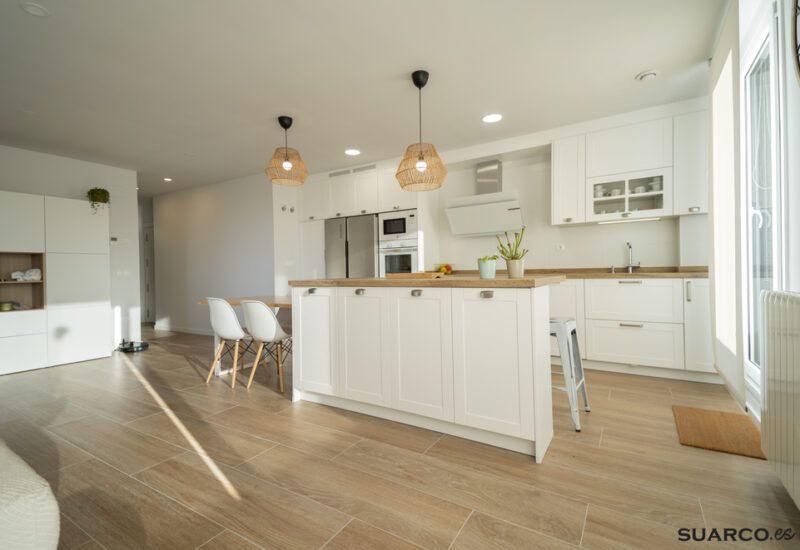 Cocina blanca con isla y encimera de madera. Cocinas Suarco