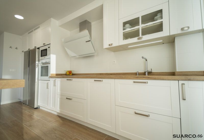 Cocina blanca con isla y encimera de madera. Cocinas Suarco