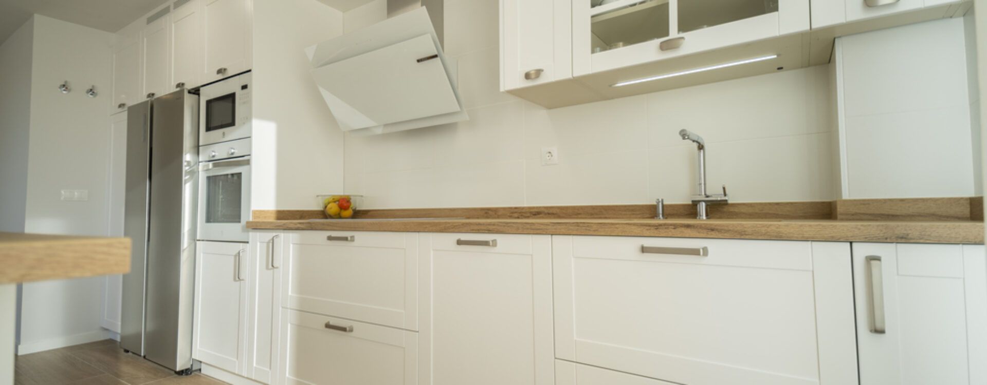 Cocina blanca con isla y encimera de madera. Cocinas Suarco