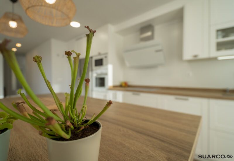 Cocina blanca con isla y encimera de madera. Cocinas Suarco